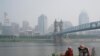 Seseorang duduk di dekat Sungai Ohio saat asap dari kebakaran hutan terlihat di pusat kota Cincinnati, Rabu, 28 Juni 2023. (AP/Joshua A. Bickel)