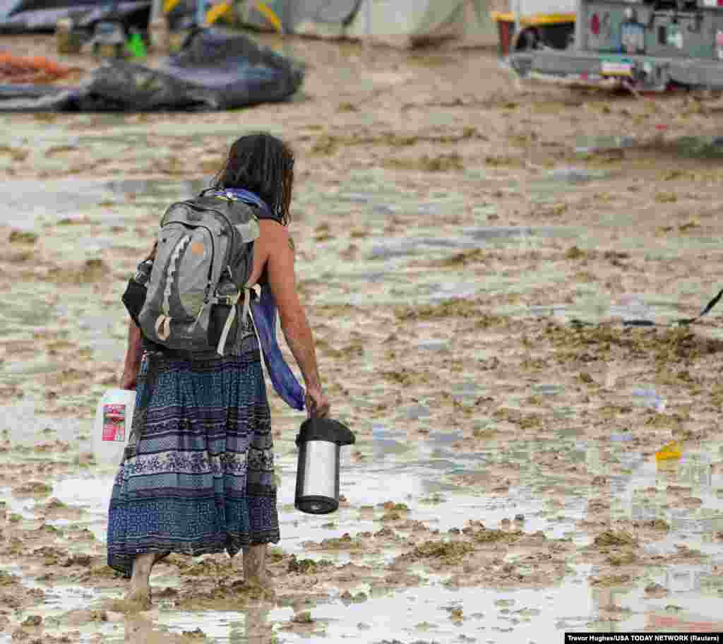 A Burning Man participant makes their way through the mud in Black Rock City, in the Nevada desert, after a rainstorm turned the site into mud, Sept. 2, 2023.
