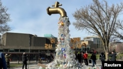Sebuah instalasi yang menggambarkan keran yang mengucurkan botol plastik dipasang oleh para aktivis di dekat venue Shaw Centre yang menjadi tempat berlangsungnya KTT plastik di Ottawa, Ontario, Kanada, pada 23 April 2024. (Foto: Reuters/Kyaw Soe Oo)