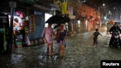 Sejumlah warga berjalan menembus banjir di tengah hujan yang terus turun sebelum topan Sitrang menerjang Dhaka, Bangladesh, pada 24 Oktober 2022. (Foto: Reuters/Mohammad Ponir Hossain)