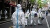 Petugas mengenakan pakaian hazmat saat melakukan penyiraman disinfektan di kawasan perumahan yang terkena lockdown di Shanghai, China, pada 15 April 2022. (Foto: Reuters/Aly Song)
