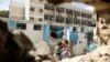 Palestinian man carries boy past UN-run school that was struck whole sheltering those displaced by Israeli ground offensive, Jebalya northern Gaza, July 30, 2014.