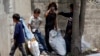 Syrian refugee children collect plastics as they stand along a street in south of Sidon, southern Lebanon, June 10, 2014.