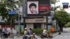 People ride their motorcycles past a digital billboard showing a sketch of the main suspect in Monday's attack on Erawan shrine, in Bangkok, Thailand, August 23, 2015.