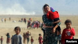 Displaced Yazidis, fleeing violence from forces loyal to the Islamic State group, head toward the Syrian border Aug. 11, 2014.