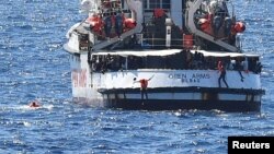 Migrants jump off the Spanish rescue ship Open Arms, close to the Italian shore in Lampedusa, Aug. 20, 2019. 