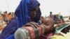 FILE - A mother quenches her malnourished child's thirst while waiting for food handouts at a health center in drought-stricken remote Somali region of Eastern Ethiopia.